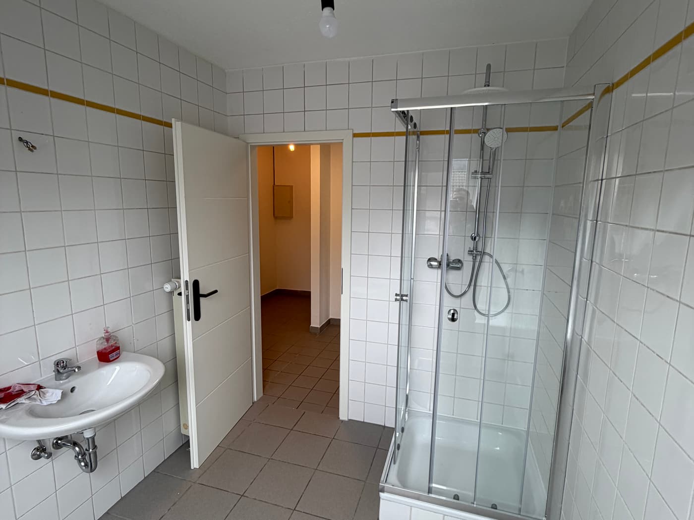 Weiß gefliestes Bad mit Duschkabine und Waschbecken